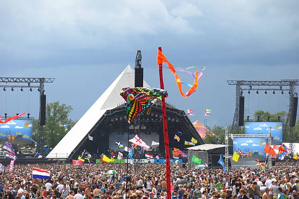 Glastonbury Festival music festival Pyramid Stage crowds stormy sky stock photo