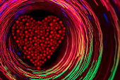 istock Glittering red heart inside the glowing multi colored circles 1360228602