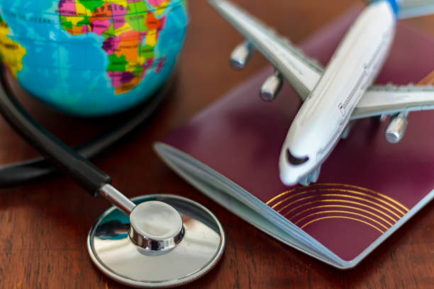 Global Healthcare and travel insurance concept. Passport Stethoscope, airplane and globe on wooden table stock photo