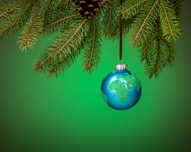 Globe christmas ornament hanging from a tree branch on green. stock photo