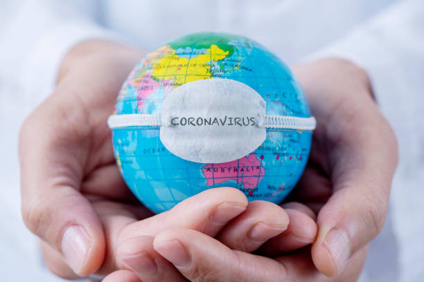globe with a mask and text coronavirus closeup of a caucasian doctor man holding a world globe with a protective mask with the word coronavirus written in it help single word photos stock pictures, royalty-free photos & images