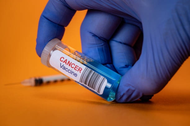 Gloved Hand Holding Cancer Vaccine with Syringe on Orange Background stock photo