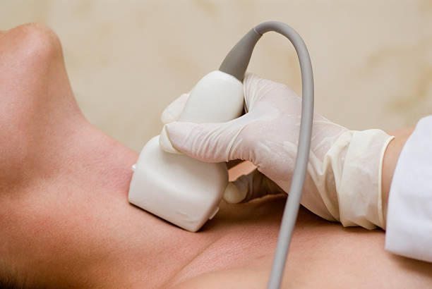 A gloved hand using an ultrasound wand on a neck  stock photo