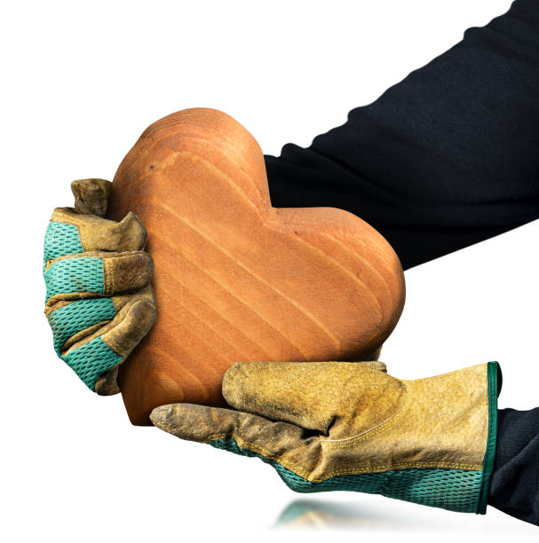 mains gantées tenant un cœur en bois brun isolé sur blanc - ouvrier coeur photos et images de collection