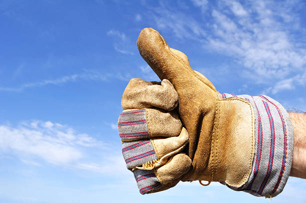 Gloved working hand giving a thumbs up sign  stock photo