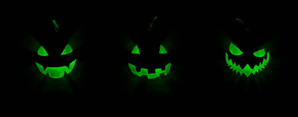 Glowing light ray green ghost face of Halloween pumpkins stock photo