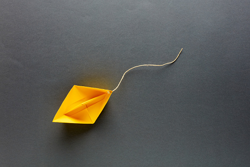 Paper boat with a cut rope goes with the flow. Go with the flow strategy in business or marketing.