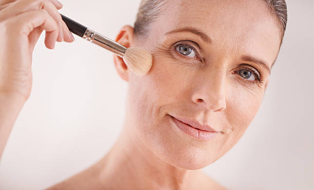 Going for that natural look Cropped portrait of an attractive mature woman applying makeup with a brush applying blush stock pictures, royalty-free photos & images