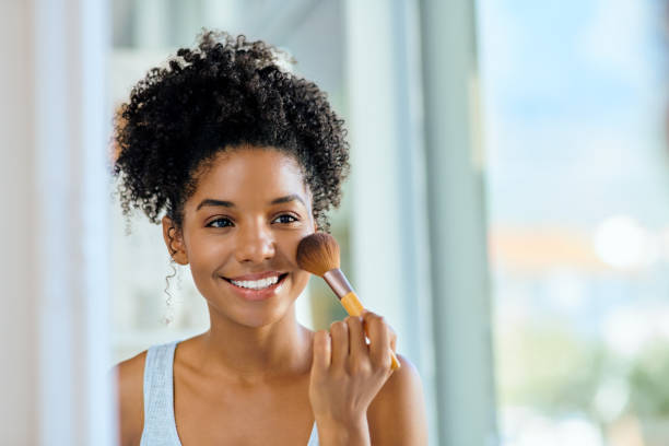 Going for that natural "no makeup" look Shot of an attractive young woman applying makeup during her morning beauty routine applying blush stock pictures, royalty-free photos & images