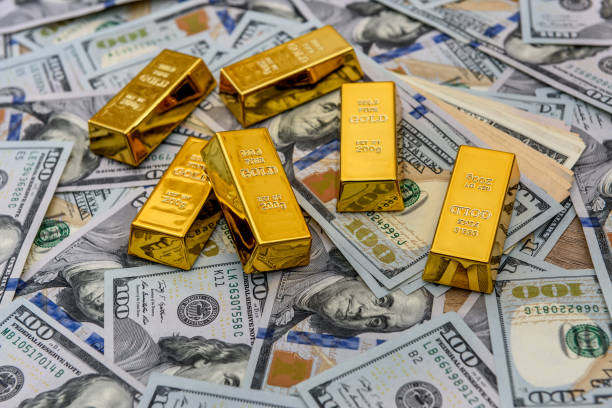 Gold bars with hundred dollar banknotes as background stock photo