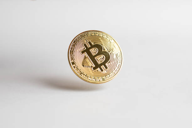 A gold Bitcoin floating above a white background stock photo