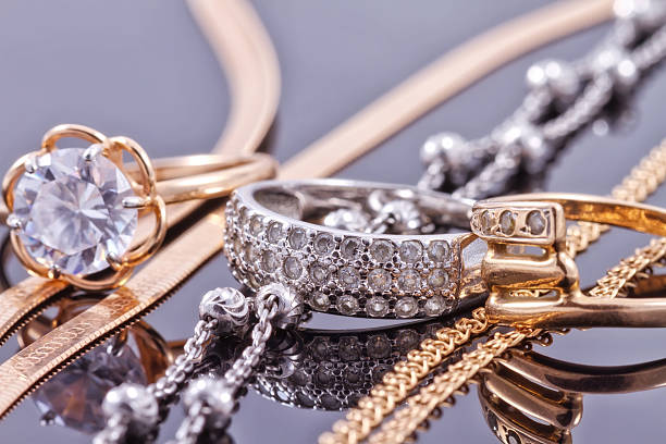 Gold, silver rings and chains Gold, silver rings and chains of different styles are lying together on the reflecting surface gold jewelry stock pictures, royalty-free photos & images