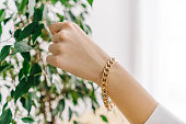 istock Golden bijouterie bracelet on woman hand. Plant. 1347209051