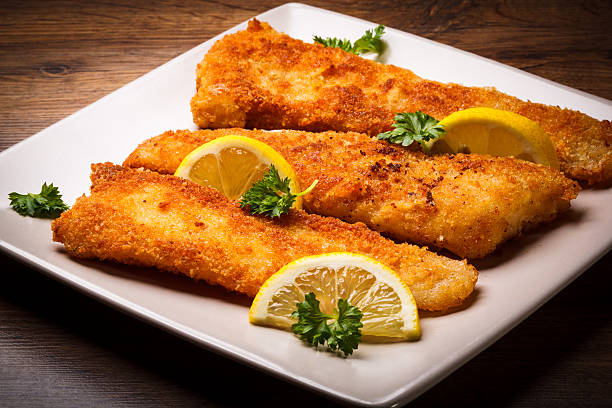 Golden cod filets, garnished with lemon slices stock photo