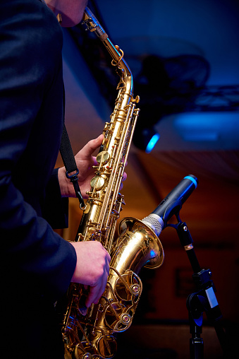 Saxophone in the hands of a musician near the microphone