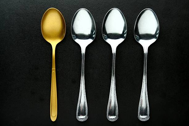 Golden Spoon among ordinary spoons stock photo