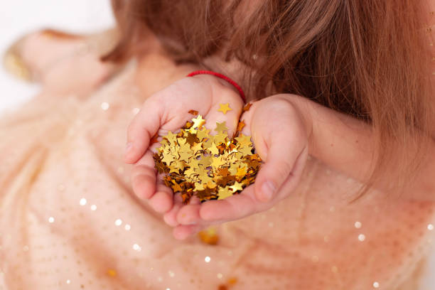 golden stars sparkle on hands and palms of child.  child hands are holding shiny golden stars confetti. festive confetti star sparkles in hands of girl. christmas, holiday concept, birthday top view. - happy birthday celebrity imagens e fotografias de stock