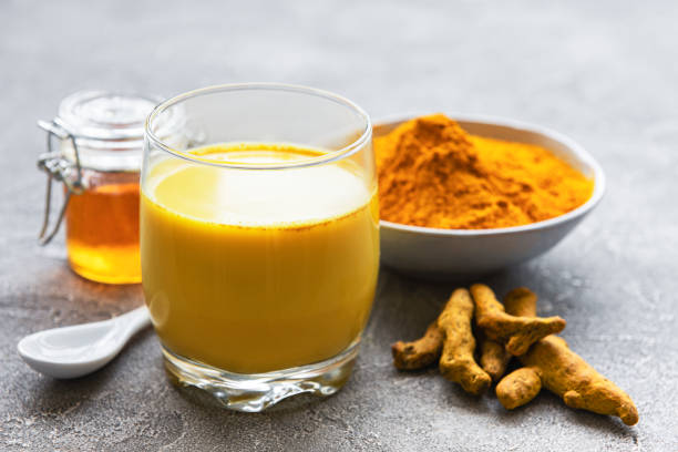 Golden turmeric milk Yellow turmeric latte drink. Golden milk with cinnamon, turmeric, ginger  and honey over grey concrete background. turmeric stock pictures, royalty-free photos & images
