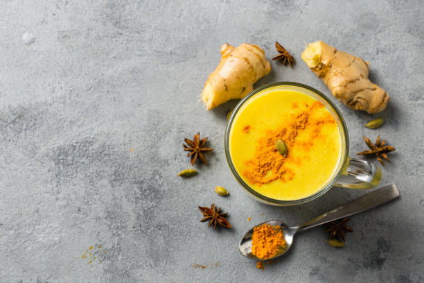 Golden yellow latte on light background. Indian drink turmeric golden milk in glass. Copy space Top view Golden yellow latte on light background. Indian drink turmeric golden milk in glass. Copy space Top view orange smoothie stock pictures, royalty-free photos & images