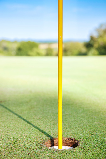 A golf flag on the putting green on a sunny summer day.