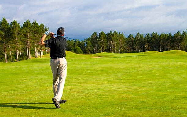 Golfer on a Michigan Golf course Golfer in a black shirt hitting an  iron shot on a Michigan golf course. michigan shooting stock pictures, royalty-free photos & images