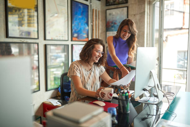 Good business relationship concept. Two caucasian young female colleagues enjoying their work, smiling. stock photo