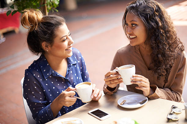Shot of two friends talking together over coffee at a...