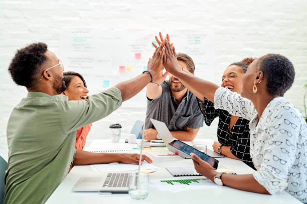 Good teamwork means a synergistic way of working towards a shared goal Shot of a group of businesspeople giving each other a high five during a meeting in an office high five stock pictures, royalty-free photos & images