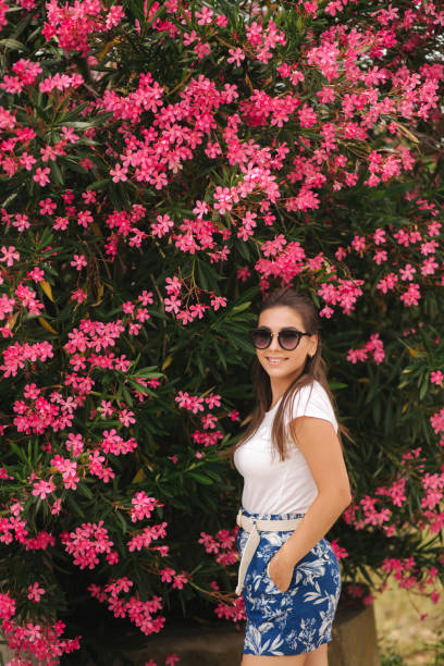 prachtige vrouw in zonnebrillen staan in prachtige bloemen. portret van gelukkig glimlachte jonge vrouw - fluisterboot stockfoto's en -beelden