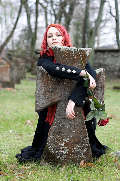 Gothic girl with a rose on cemetery stock photo