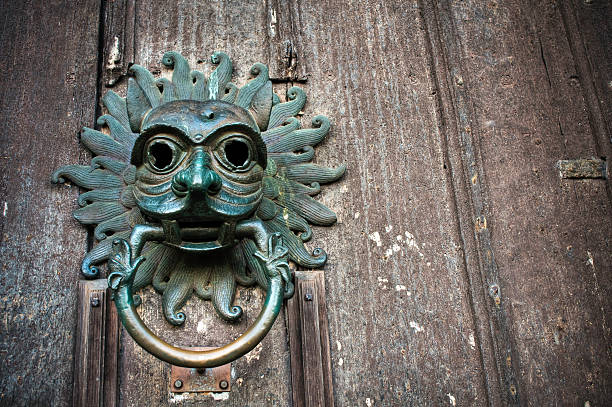 Gothic sanctuary door knocker, Durham Cathedral This impressive bronze is at the north entrance of the cathedral and is a near perfect replica of the twelfth century original which can be seen in the Treasury Museum. It represents the ancient privelege of sanctuary once granted to criminal offenders at Durham cathedral. Criminals could seek refuge at Durham by using the knocker. They would confess the details of his crime before a coroner and was allowed to remain inside the cathedral for a period of thirty seven days. Subtle desaturated HDR image with a shallow depth of field and a ProPhoto RGB profile for maximum color fidelity and gamut. Space for copy and text. Durham Cathedral stock pictures, royalty-free photos & images