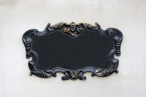 Vintage gothic style blank black metal wall plaque or sign with decorative swirly edges with gold coloring