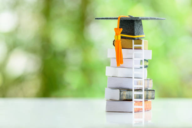 Graduate study abroad program to broaden learner's world view, education concept Graduation cap, foreign books on a table. Graduate study abroad program to broaden learner's world view, education concept Graduation cap, foreign books on a table. The image depicting students attempt to study from a distance or learning from home. business associate degree? stock pictures, royalty-free photos & images