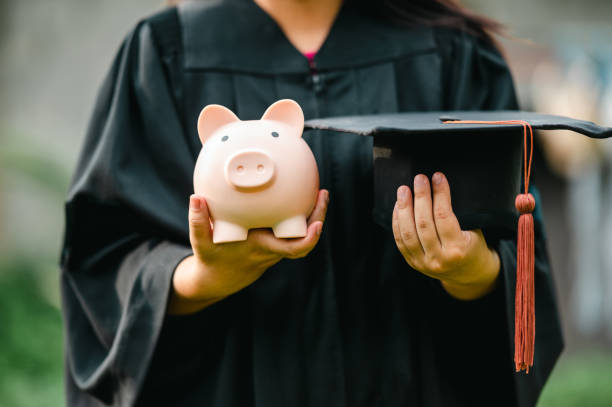 graduates holding piggy banks saving concept stock photo