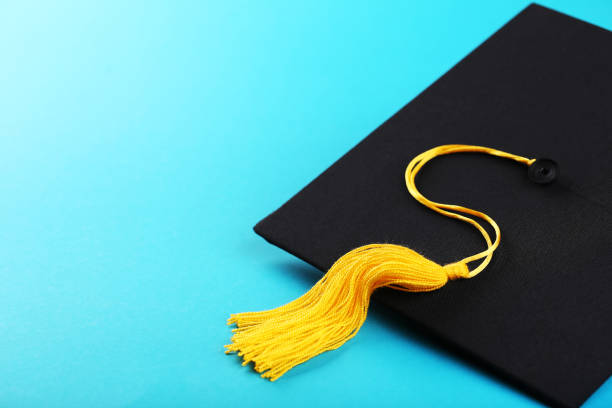 Graduation cap on blue background stock photo