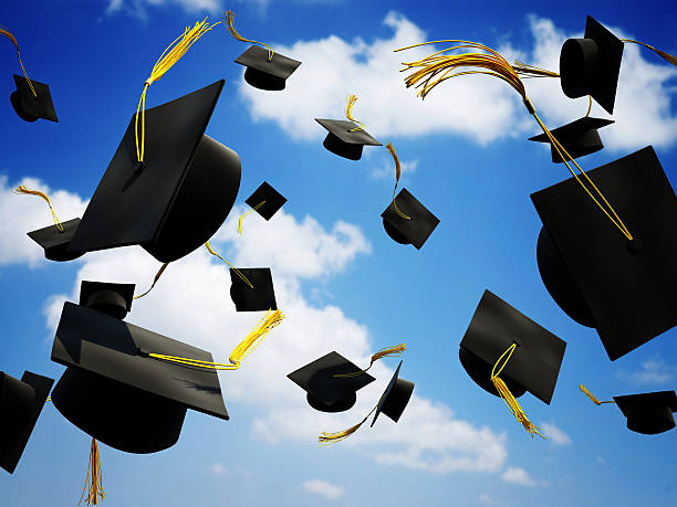 Graduation caps thrown in the air stock photo