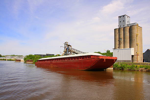 Grain Barge on Mississippi River This barge on the Mississippi River in eastern Iowa is taking on a load of grain, either corn or soybeans, from area farms.  barge stock pictures, royalty-free photos & images