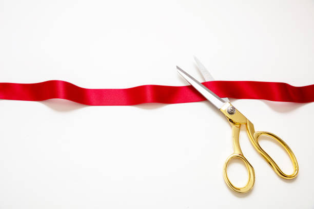Grand opening, ribbon cut, overhead of gold scissors and red satin satin isolated on white stock photo