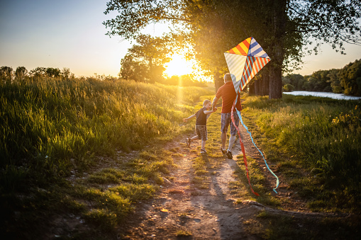 Photo of boy and grandpa with a kite in nature on a sunny day.