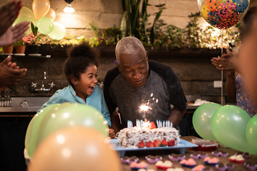 Grandfather and granddaughter celebrating birthday together at home