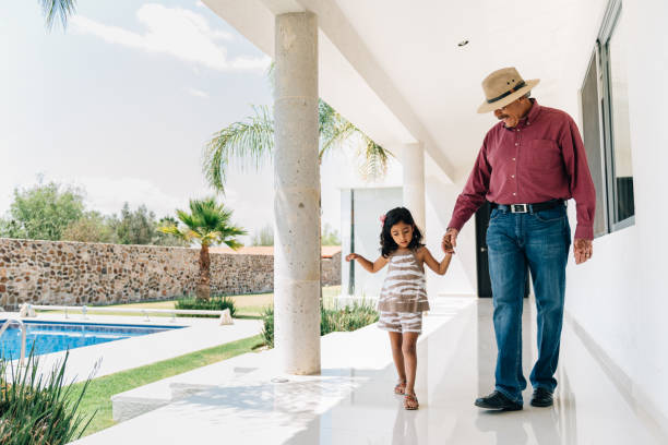 Grandfather and granddaughter walking holding hands Grandfather and granddaughter walking by the hand on the poolside of a Holiday Villa vacation rental photos stock pictures, royalty-free photos & images