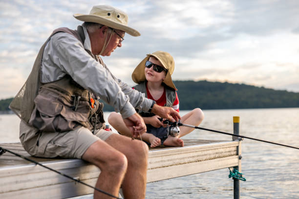 Grandfather and Grandson Fishing At Sunset in Summer, Quebec, Canada stock photo