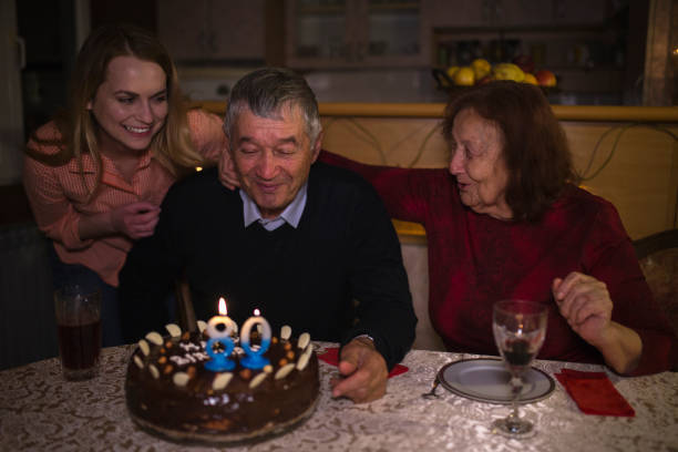 Grandfather blowing candles and celebrates the eightieth birthday stock photo
