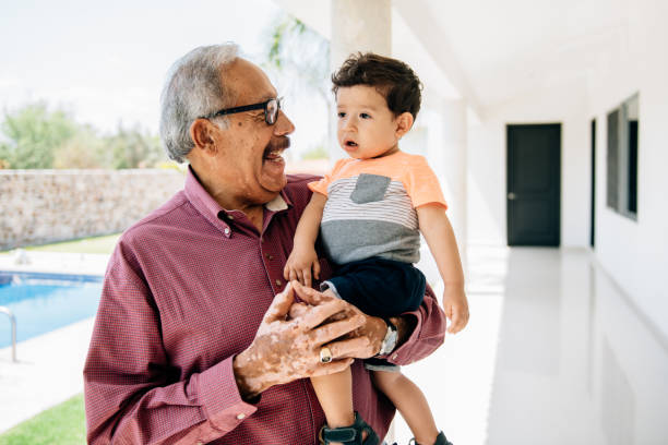 Grandfather holding grandson toddler by the swimming pool stock photo