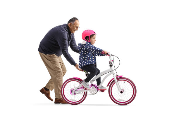 Grandfather teaching a little girl to ride a bicycle stock photo