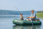istock grandfather with grandson together fishing from inflatable boat 1340209849