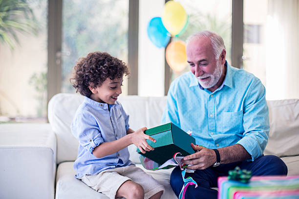 Grandfather's birthday gift Middle Eastern family celebrating the kid's birthday, grandfather is giving his grandson the birthday present. old arab man stock pictures, royalty-free photos & images