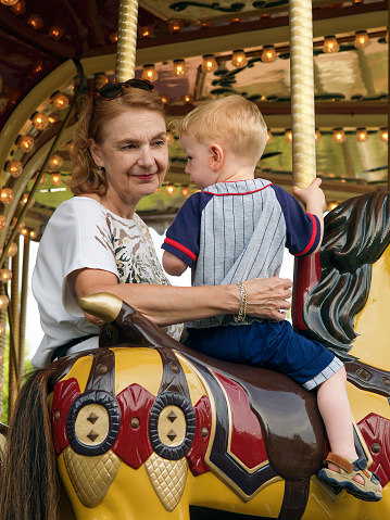 Branson, MO USA - June 4, 2004: A grandmother watches her grandson ride on a vintage carousel at Celebration City Theme Park in Branson, Missouri. The early 20th century themed park opened in 2003 and closed in 2008 after five years of poor attendance.