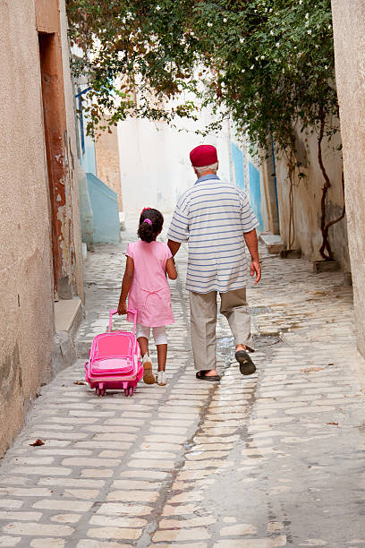 Grandpa and granddaughter Tunisia, Sousse - October 07, 2013: Grandfather  holding his granddaughter's hand walking back from school. tunisian girls stock pictures, royalty-free photos & images