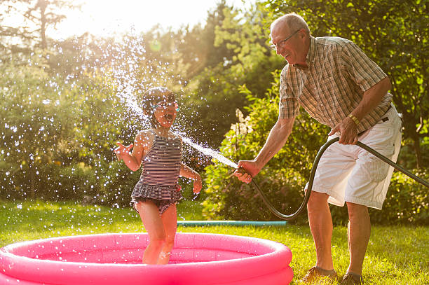 Grandparent and grandkid playing with hose stock photo